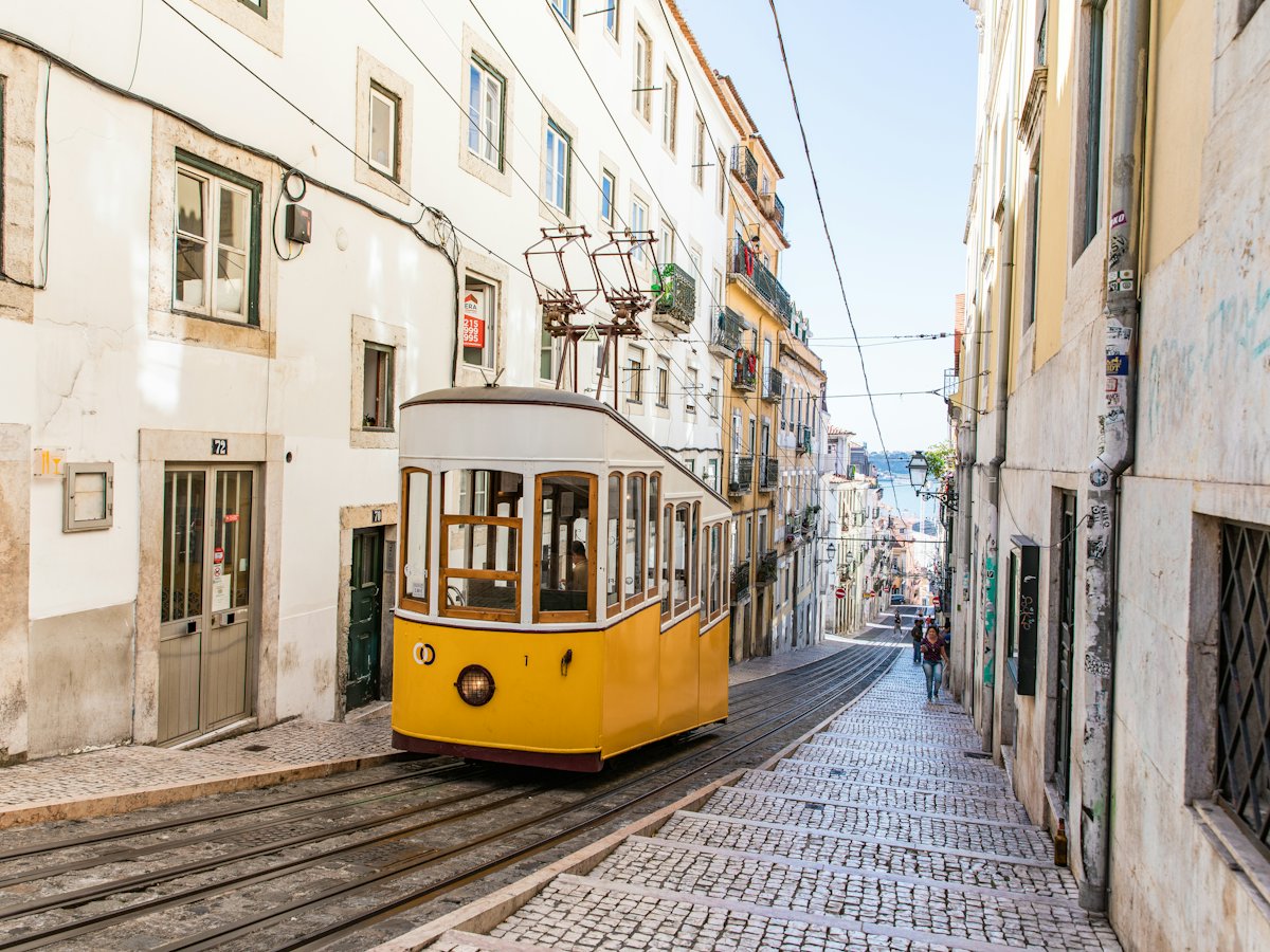 Elétrico amarelo numa rua de calçada em Lisboa